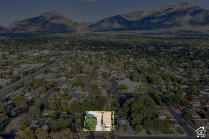 Aerial perspective of a property featuring a swimming pool, mature trees, and a mountain backdrop