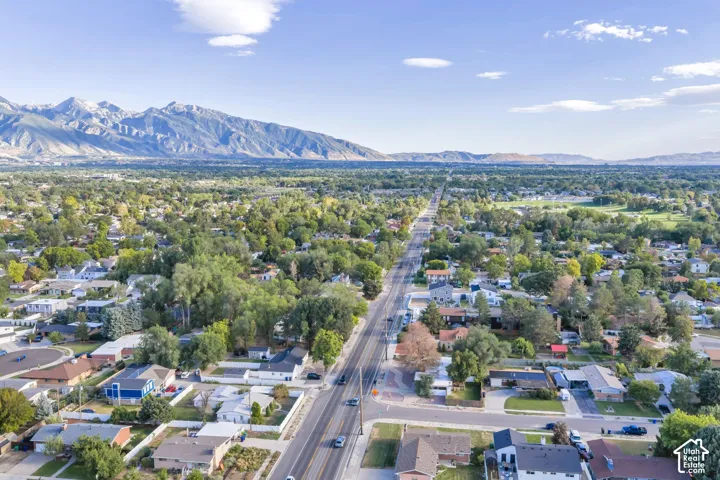 Aerial perspective of a residential neighborhood featuring established mature trees and a prominent mountain range backdrop