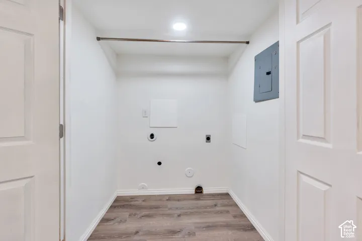 Utility space featuring wood-finish flooring, recessed ceiling lighting, a metal clothing rod, and an integrated electrical service panel