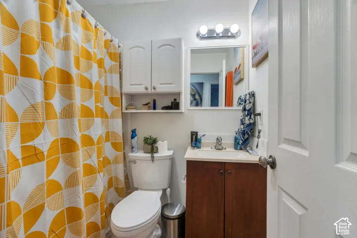 Bathroom featuring a dark wood-finish vanity with an integrated sink, white-finish wall-mounted cabinetry, a rectangular mirror, and a three-bulb vanity light fixture