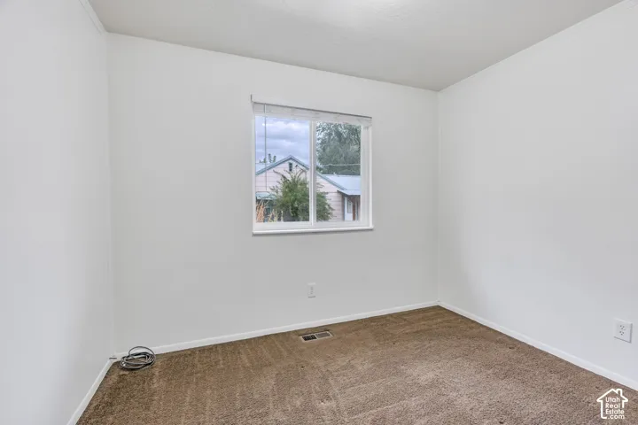 Interior room featuring neutral wall paint, carpeting, and a sliding window with integrated blinds