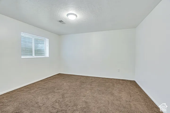 Room featuring neutral carpeting, white walls, and a sliding window
