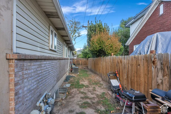 Exterior side yard featuring horizontal siding, a masonry base, and a full-height wood privacy fence