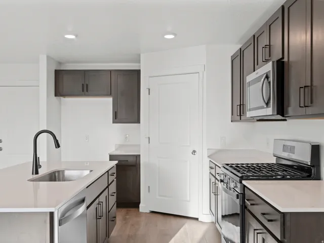 Modern kitchen featuring dark wood-finish cabinetry, light countertops, and stainless steel appliances