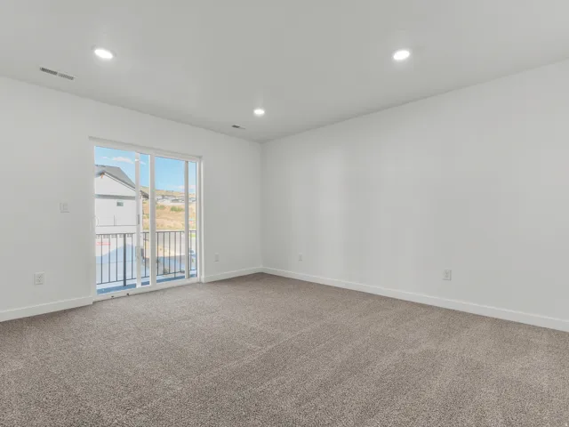 Recessed ceiling lighting, sliding glass door, private balcony with black metal railing, white walls, and gray carpet flooring
