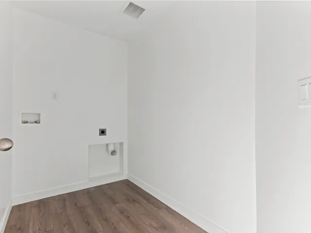 Laundry utility area featuring wood-finish flooring, white walls, and a ceiling vent