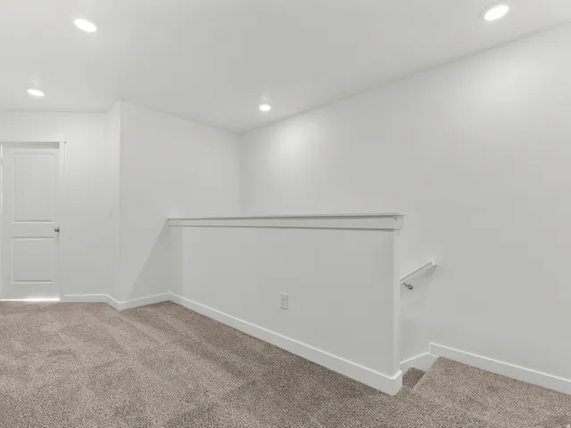 Recessed lighting, neutral wall finishes, plush carpet flooring, white trim, and a contemporary stair railing