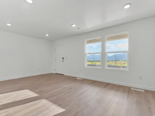 Wood-finish flooring, recessed lighting, and white walls with two windows featuring mountain scenery