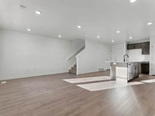 Open-concept living space featuring wood-finish flooring, recessed lighting, and a contemporary kitchen island with a black faucet