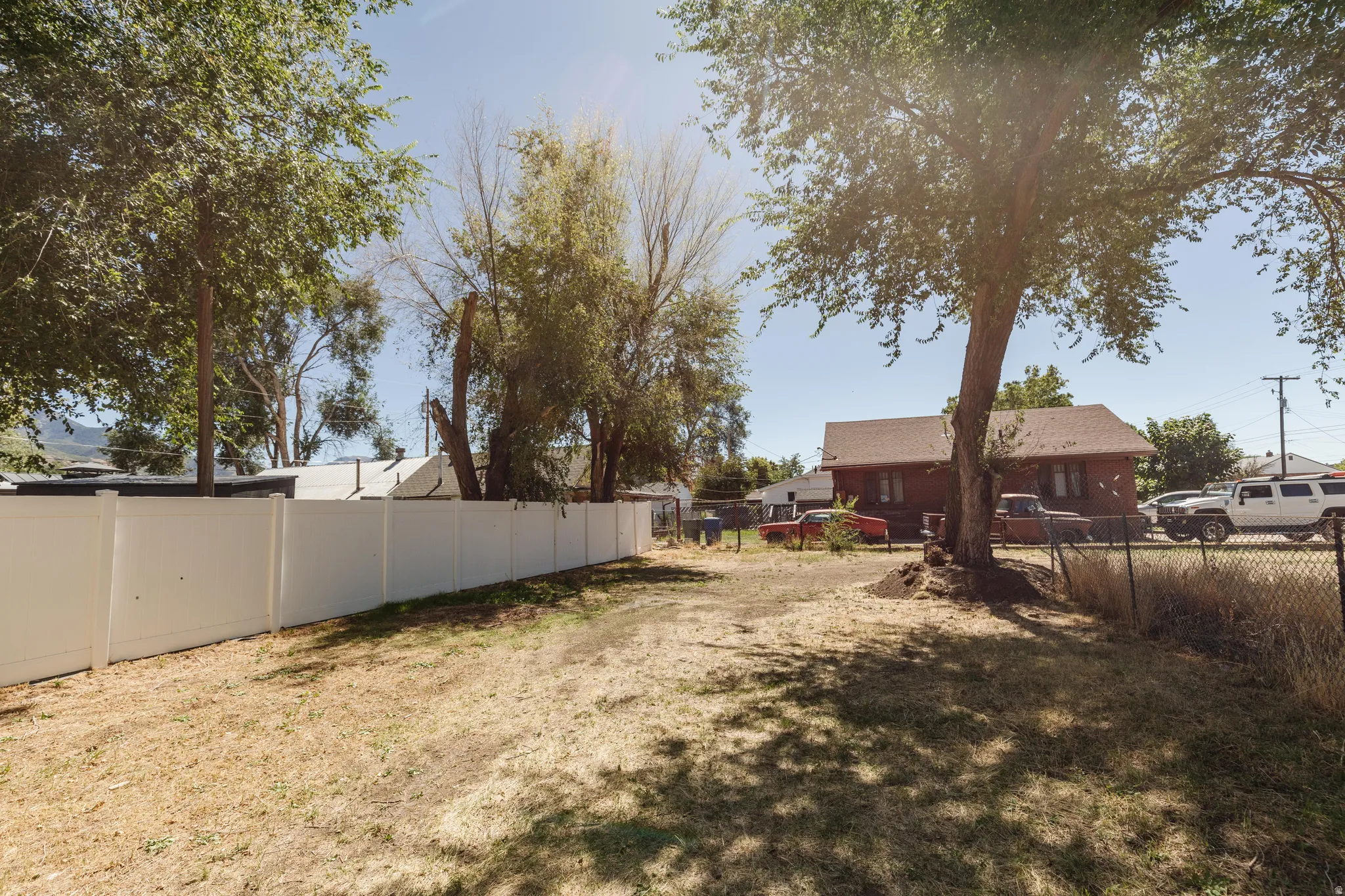 White panel fencing, mature trees, and a chain-link fence define the property perimeter