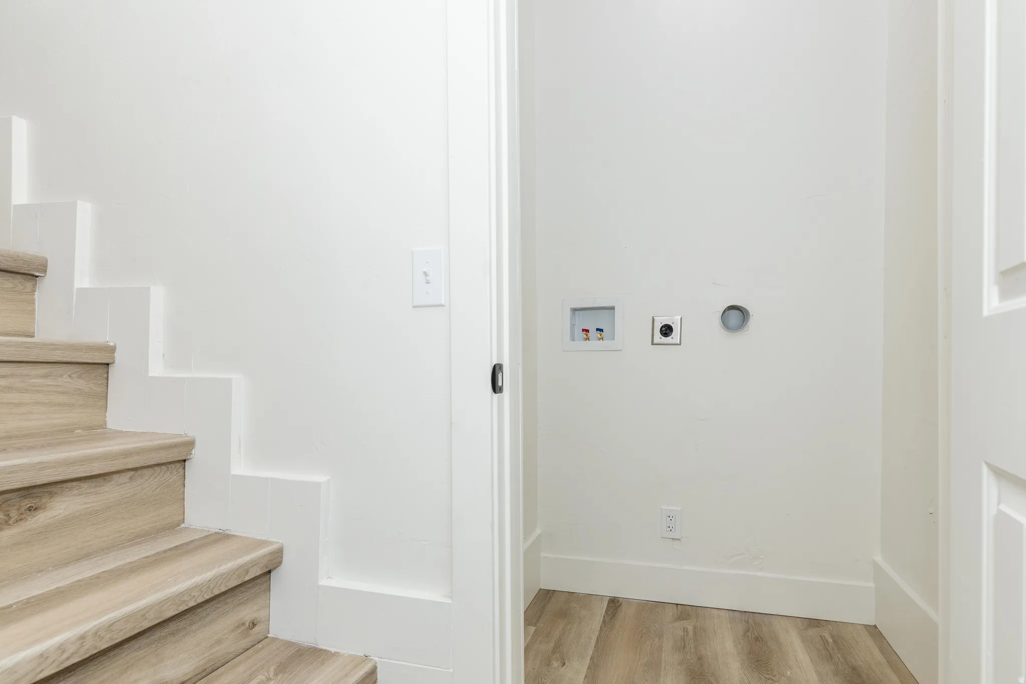 Wood-finish flooring, white walls, and a dedicated laundry area