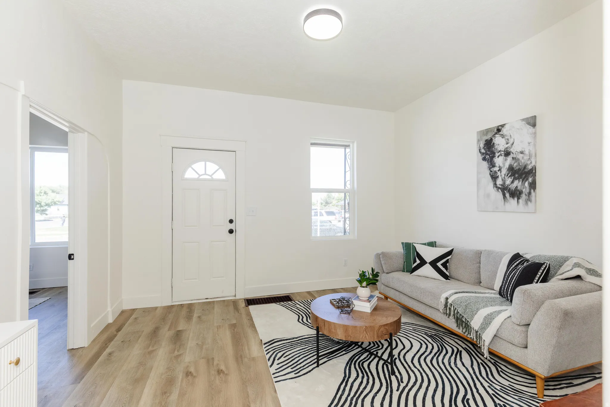 Recessed ceiling lighting, wood-finish flooring, white paneled entry door with an arched window, and a single pane window