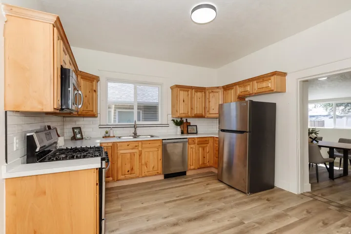 Kitchen featuring wood cabinetry, white countertops, white subway tile backsplash, and wood-finish flooring