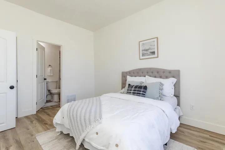 White interior walls, wood-finish flooring, white solid core doors, and a partial bathroom with toilet