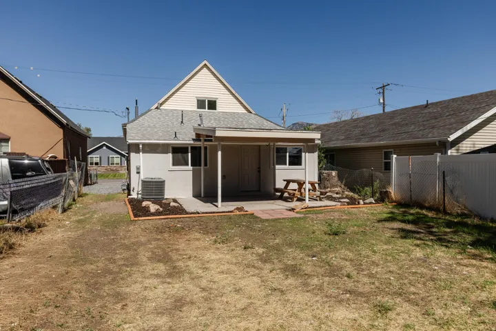 Rear exterior with a covered patio, multiple windows, and a fenced perimeter