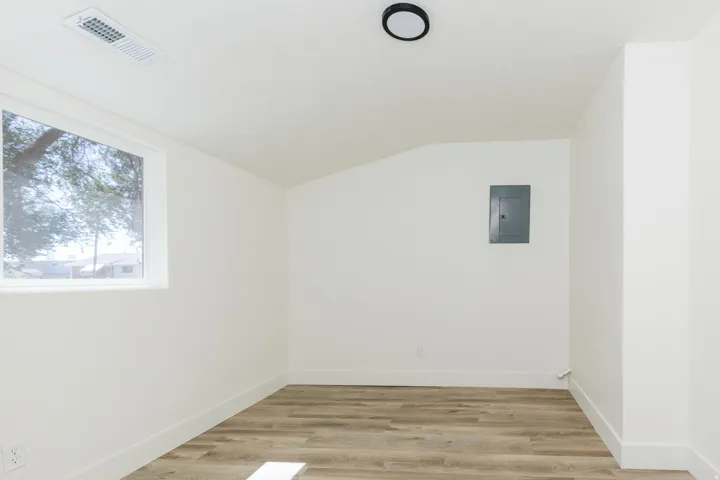 Recessed window, wood-finish flooring, crisp white walls, contemporary ceiling light, utility panel