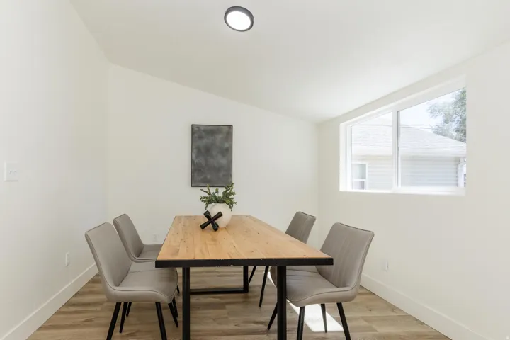 Vaulted ceiling, recessed lighting, wood-finish flooring, white walls, and a large window