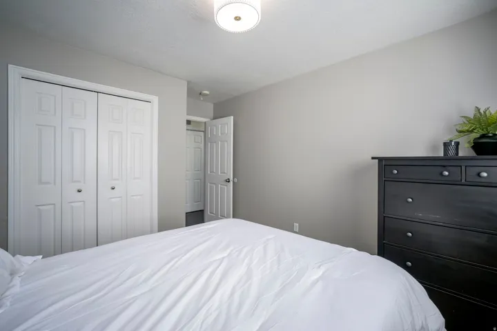 White bi-fold closet doors, light neutral wall paint, and a semi-flush mount ceiling light