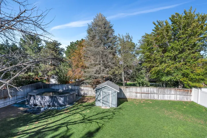 Expansive backyard featuring a manicured lawn, wood fencing, and an above-ground pool