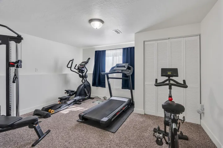 Carpeted room with a ceiling-mounted light fixture, louvered bi-fold closet doors, and painted walls with a chair rail