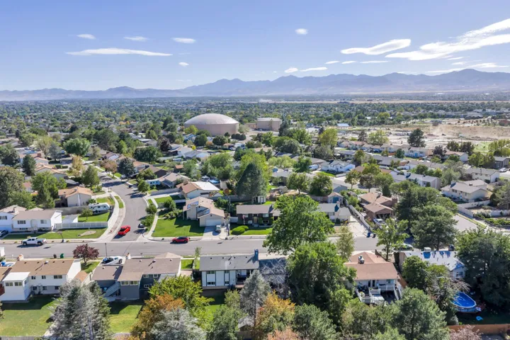 Residential neighborhood with mature trees, paved streets, and a mountainous backdrop