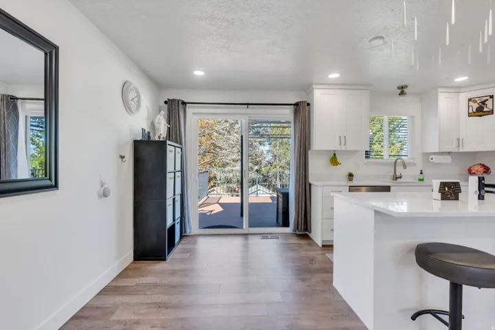 Wood-finish flooring, white cabinetry, integrated stainless steel appliances, and a sliding glass door to an outdoor deck