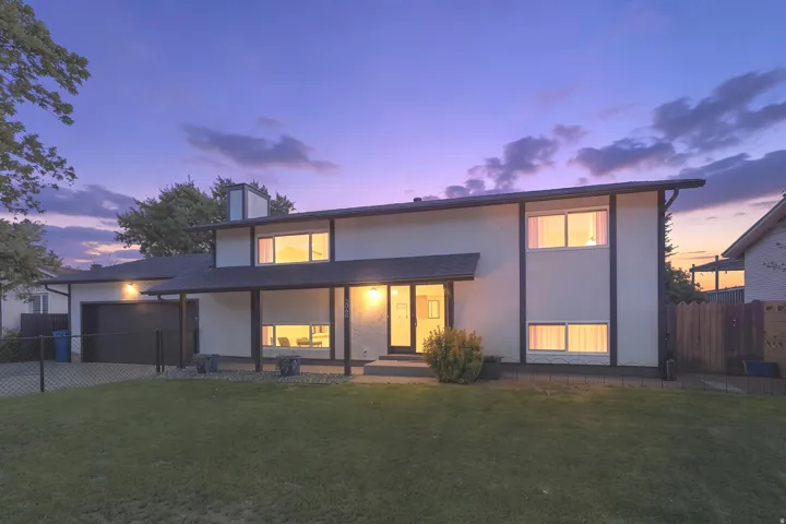 Split-level exterior featuring light-colored siding, dark trim, an attached garage, and a covered front entry