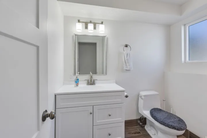 White vanity with a solid surface countertop, undermount sink, and brushed nickel faucet