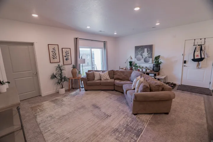Recessed ceiling lighting, light gray interior door, sliding glass door, white walls, and gray wall-to-wall carpeting