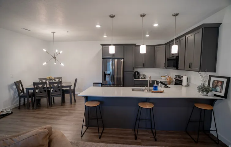 Open-concept kitchen and dining area featuring wood-finish flooring, recessed lighting, and a kitchen island with pendant lighting