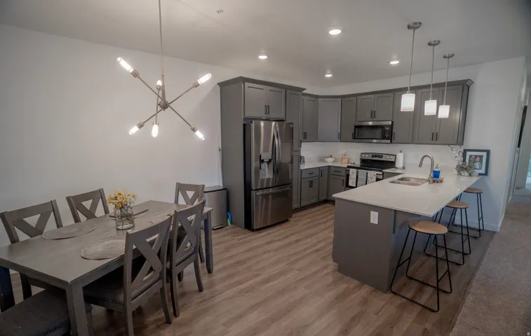 Contemporary kitchen featuring gray cabinetry, stainless steel appliances, white countertops, and pendant lighting
