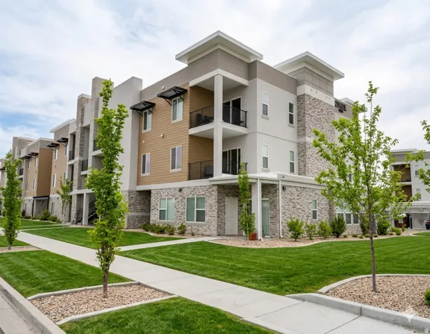 Multi-story building featuring a stucco and stone veneer exterior, private balconies with black railings, and covered entryways