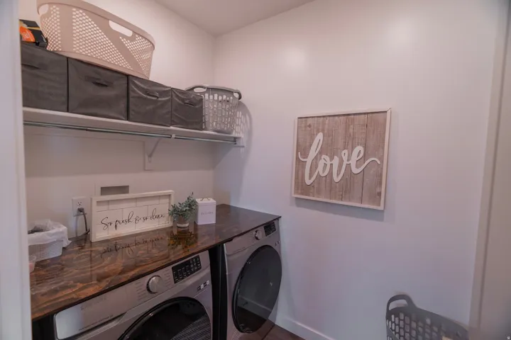 Built-in shelving for storage, wood-finish countertop, and front-loading laundry appliances