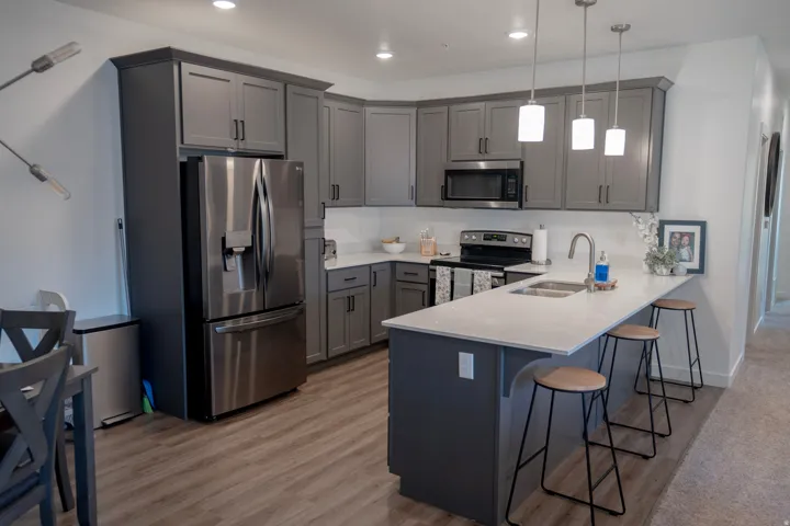 Kitchen featuring gray cabinetry, stainless steel appliances, a white countertop island, and wood-finish flooring