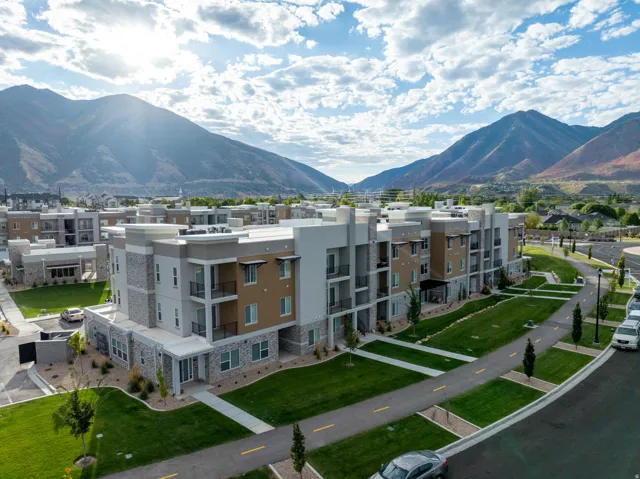 Modern multi-story buildings featuring stone and stucco exteriors, private balconies, and surrounding green spaces