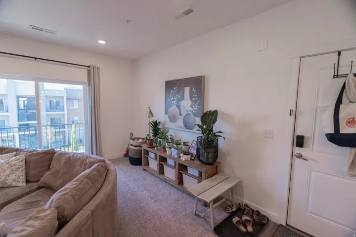 Sliding glass door leading to a balcony, recessed ceiling lighting, wall-to-wall carpeting, white interior door, and white painted walls