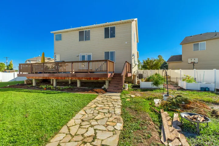Elevated wood-tone deck with railing, natural stone pathway, and manicured lawn