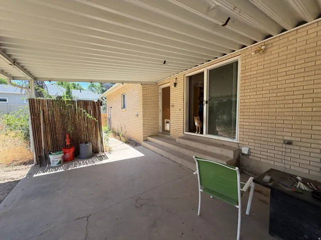 Covered patio with a concrete surface, brick exterior, and sliding glass door