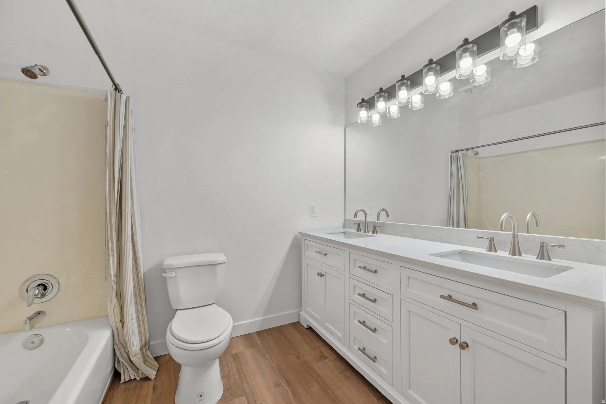 Double vanity with white cabinetry and integrated sinks, brushed nickel fixtures, and a wide mirror