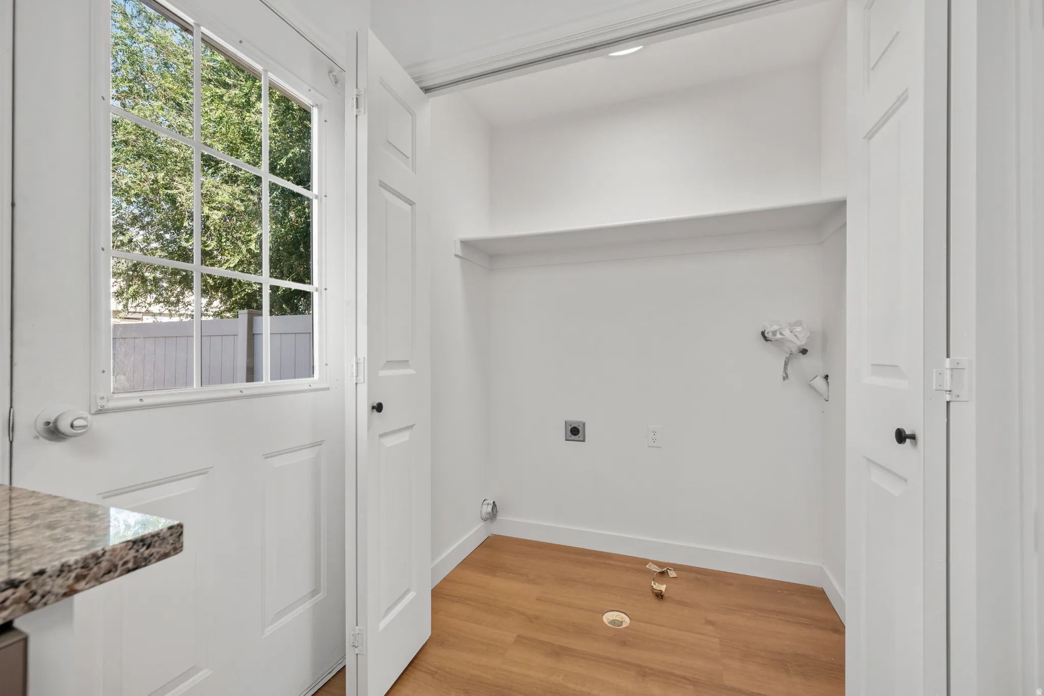 Dedicated laundry area with a built-in shelf, wood-finish flooring, and a windowed exterior door