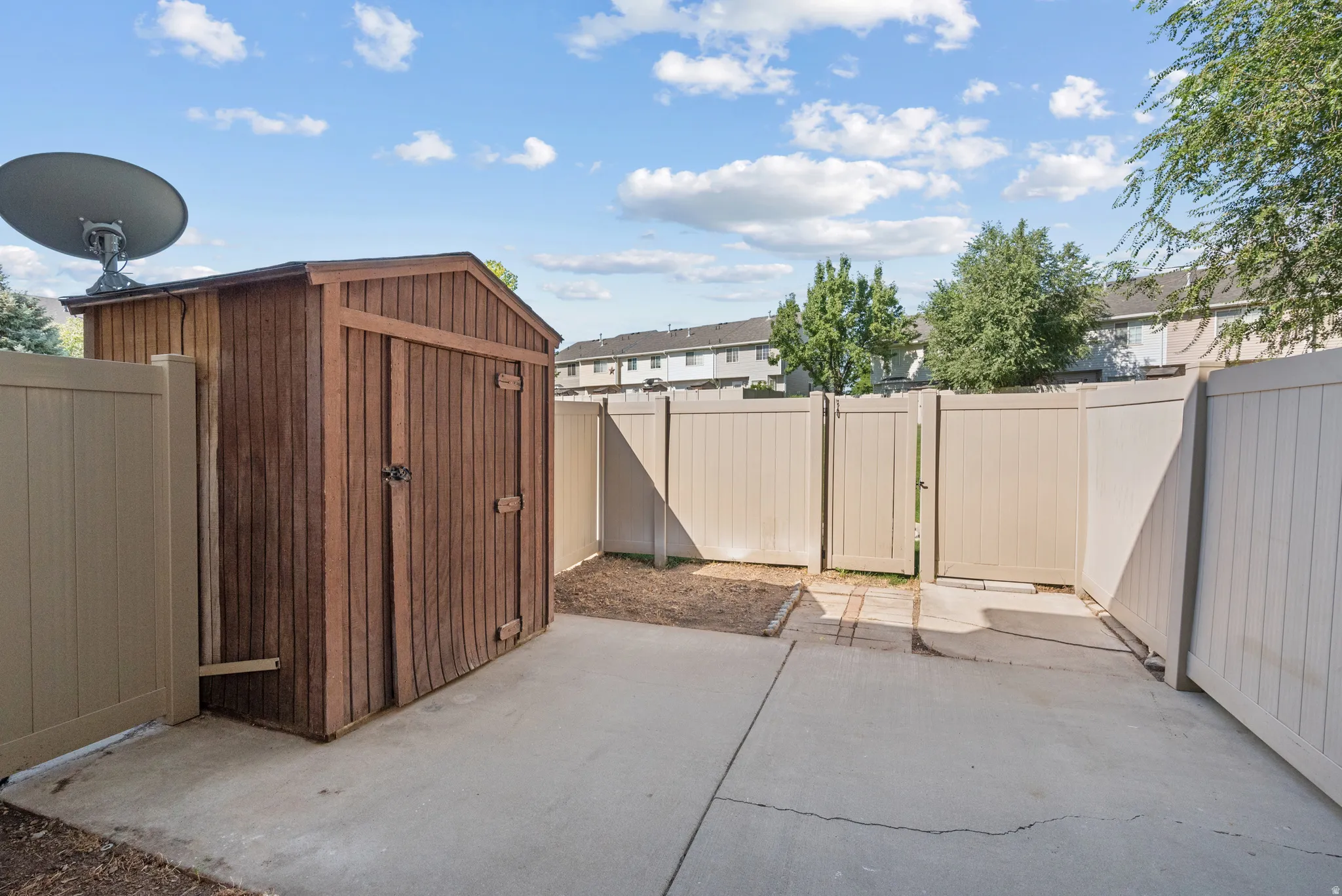 Private patio area featuring a storage shed, concrete paving, and light-toned fencing
