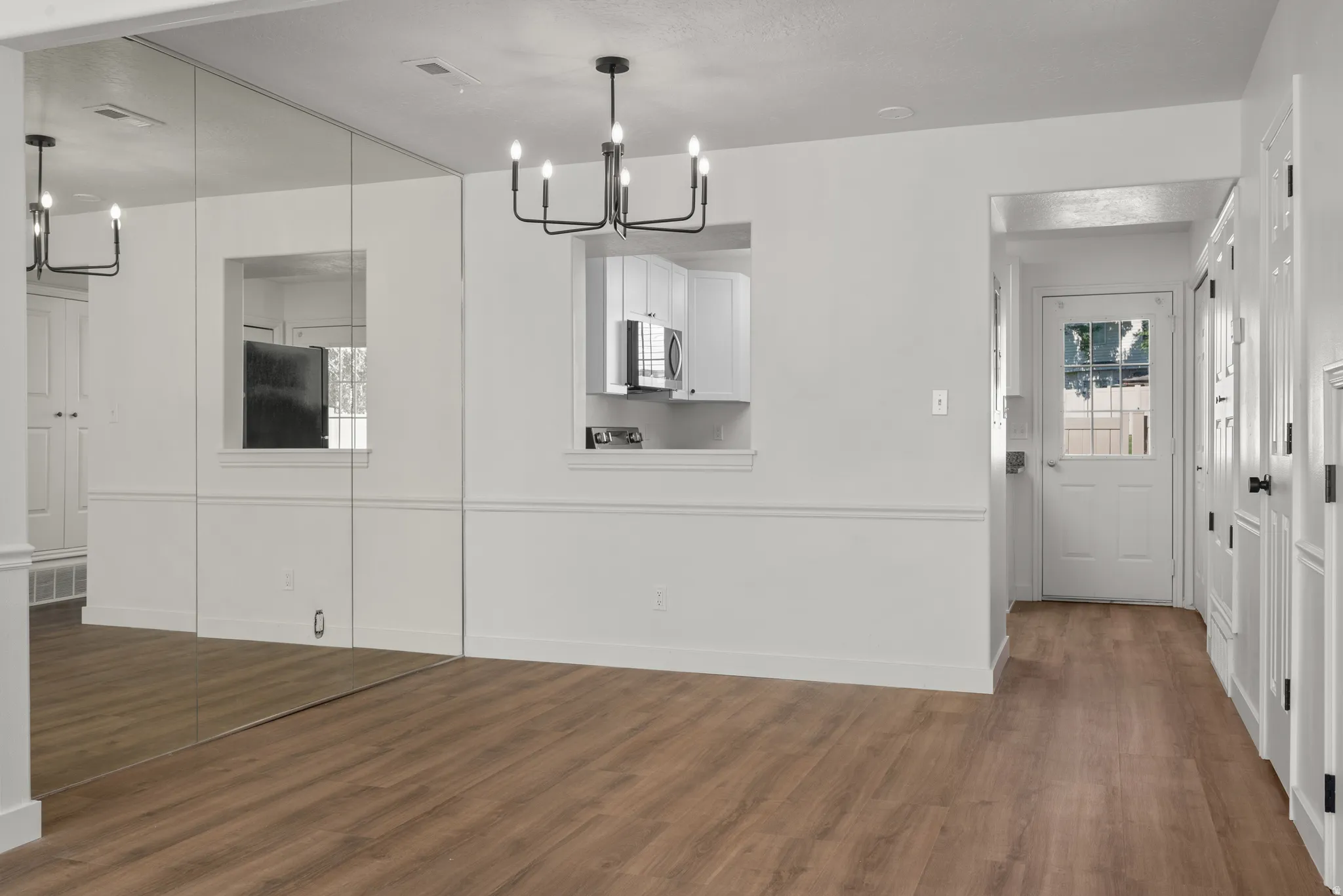 Wood-finish flooring, wainscoting details, and a modern chandelier