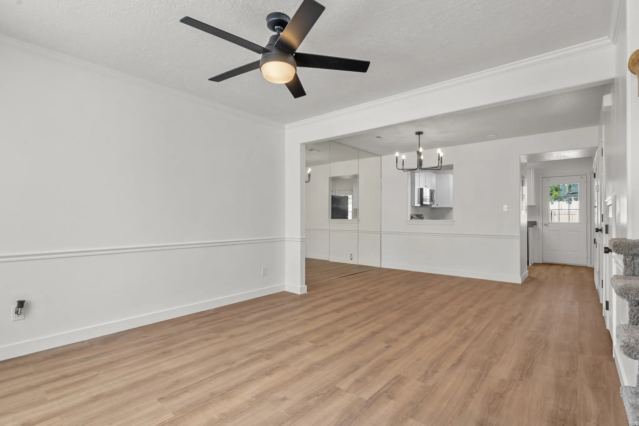 Wood-finish flooring, crown molding, chair rail molding, and a modern ceiling fan with integrated lighting