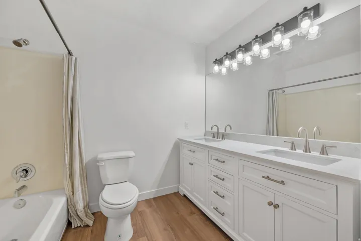 Double vanity with white cabinetry and integrated sinks, brushed nickel fixtures, and a wide mirror