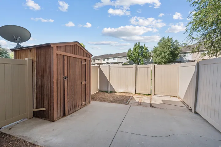 Private patio area featuring a storage shed, concrete paving, and light-toned fencing