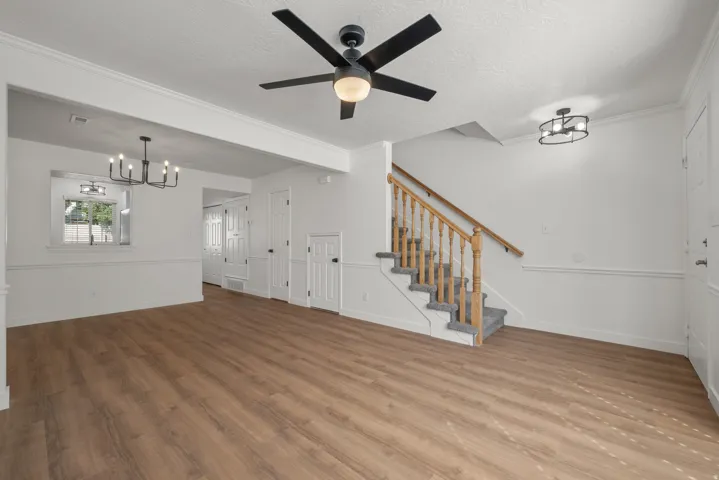 Spacious living area featuring wood-finish flooring, a contemporary ceiling fan, and a chandelier