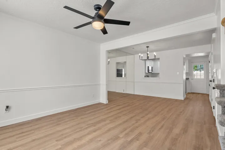 Wood-finish flooring, crown molding, chair rail molding, and a modern ceiling fan with integrated lighting