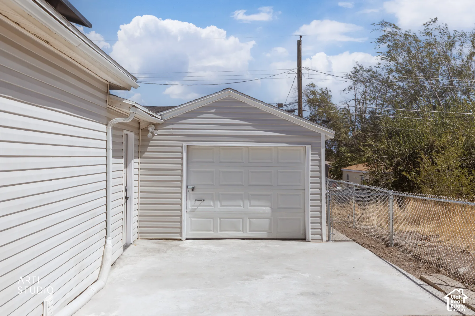 Attached garage with a white panel door and concrete driveway