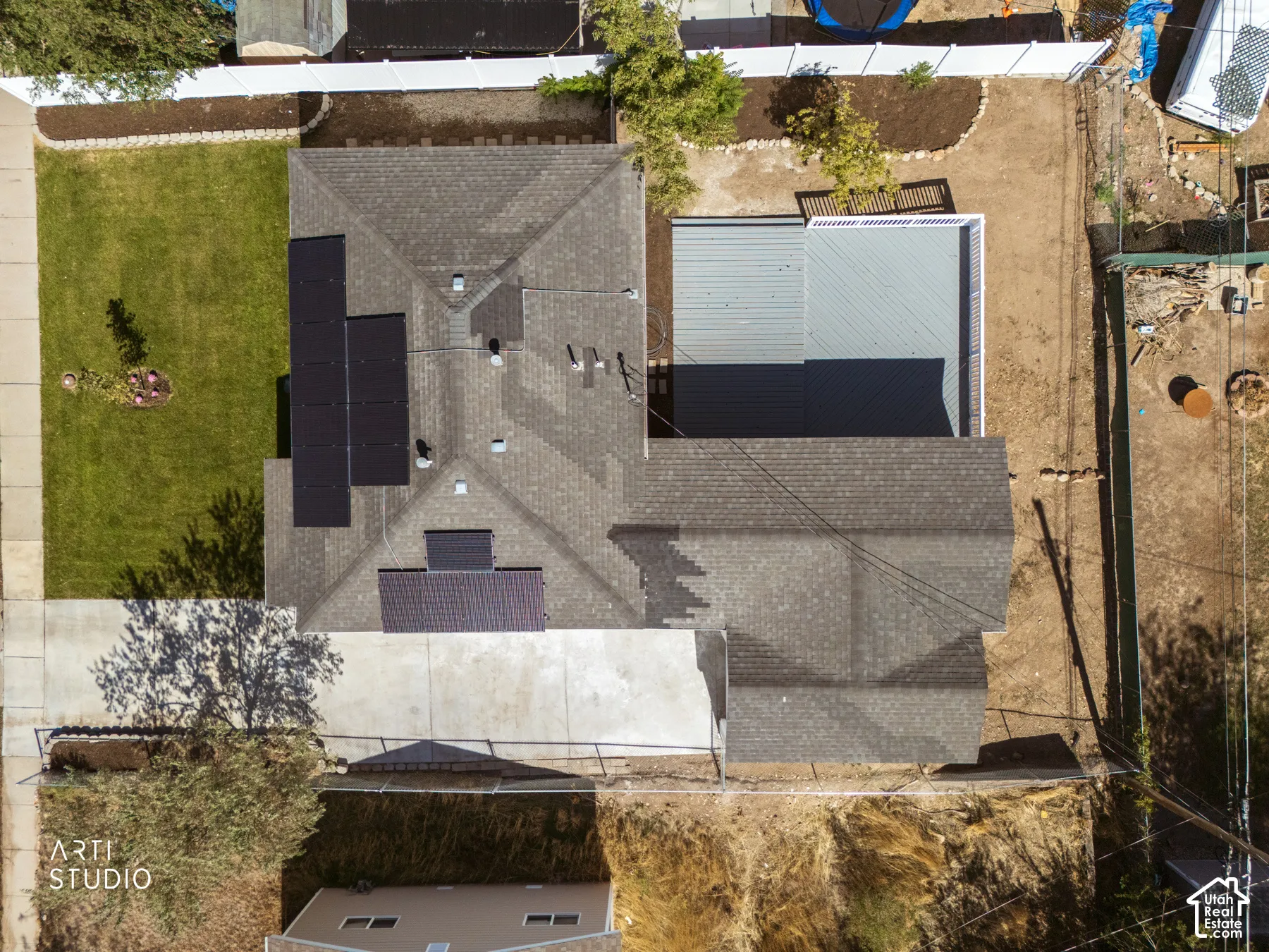 Asphalt shingle roofing, solar panel arrays, concrete driveway, front lawn, rear open-air structure