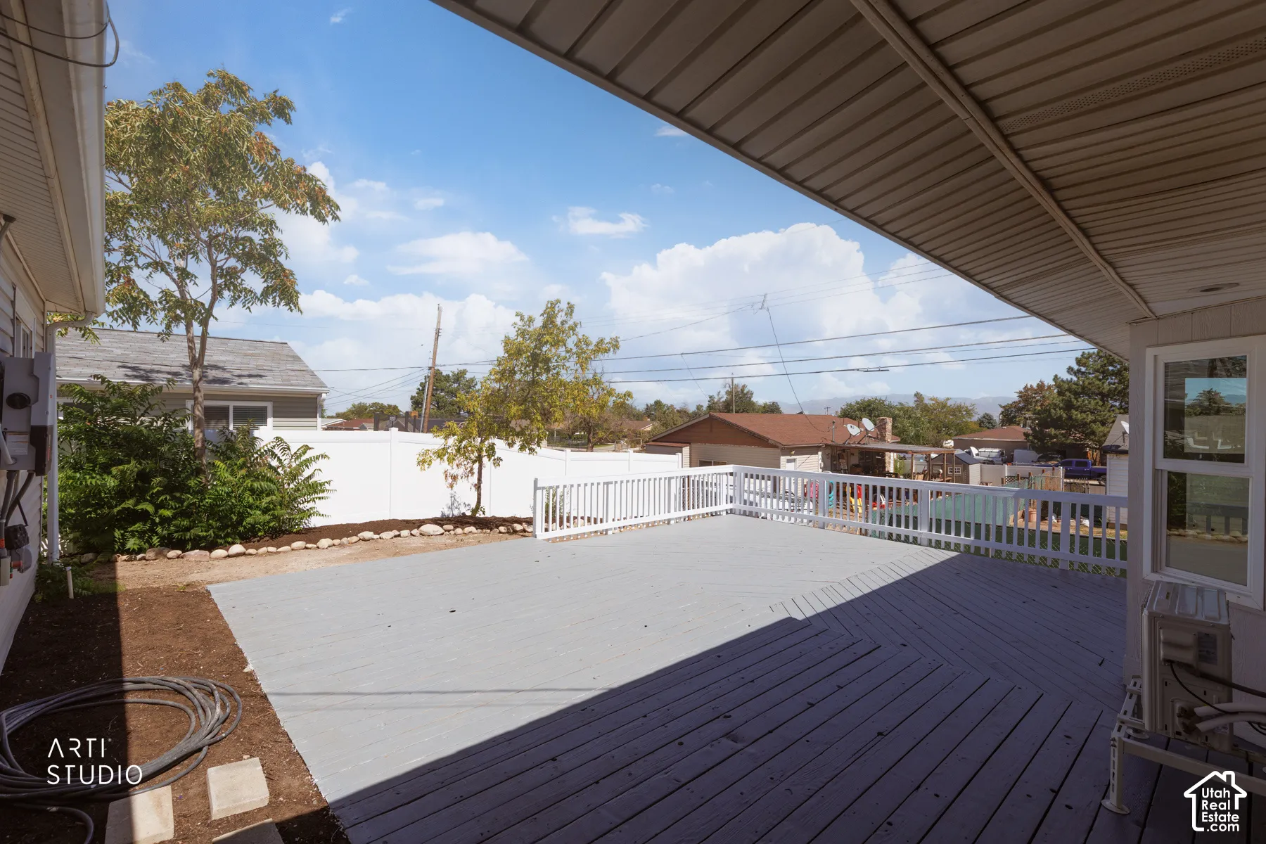 Expansive outdoor deck with a protective overhead covering and white railing